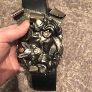 Large intricate statement belt buckle on thick black leather belt adjustable